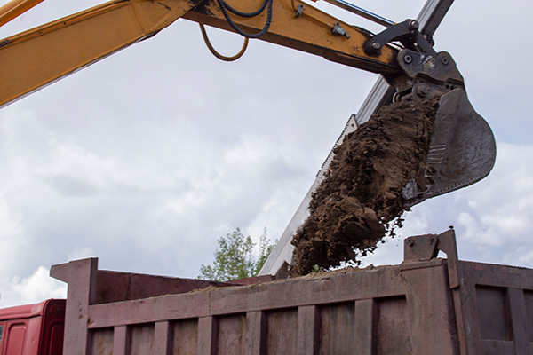 Soil loading by excavator bucket into the dump truck body