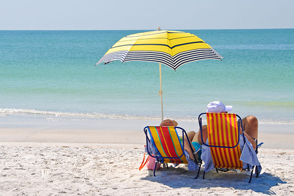 Couple enjoying the beach from their lawn chairs, with umbrella