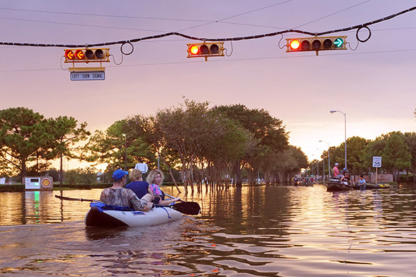 Boat with people paddle over flooded streets.