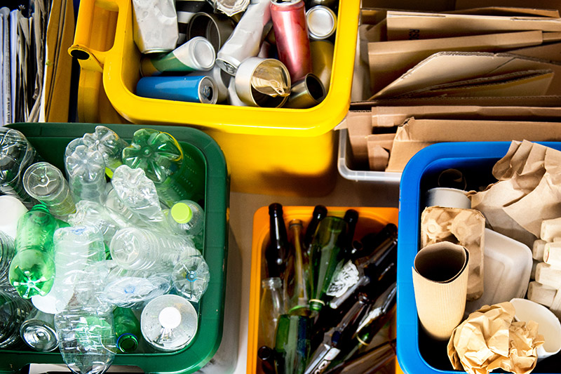 Sorted recycling items such as plastic bottles, cans, cardboard and paper in bins