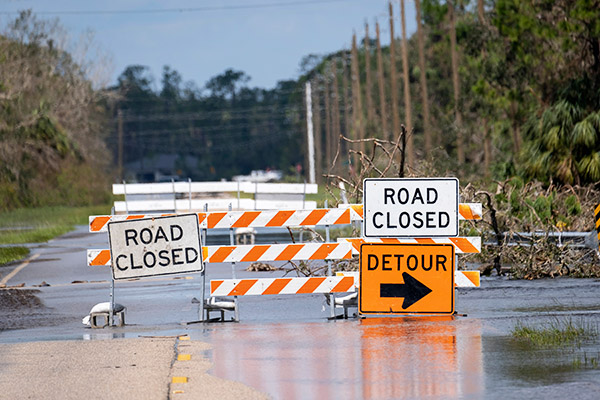 Hurricane flooded street with road closure signs.